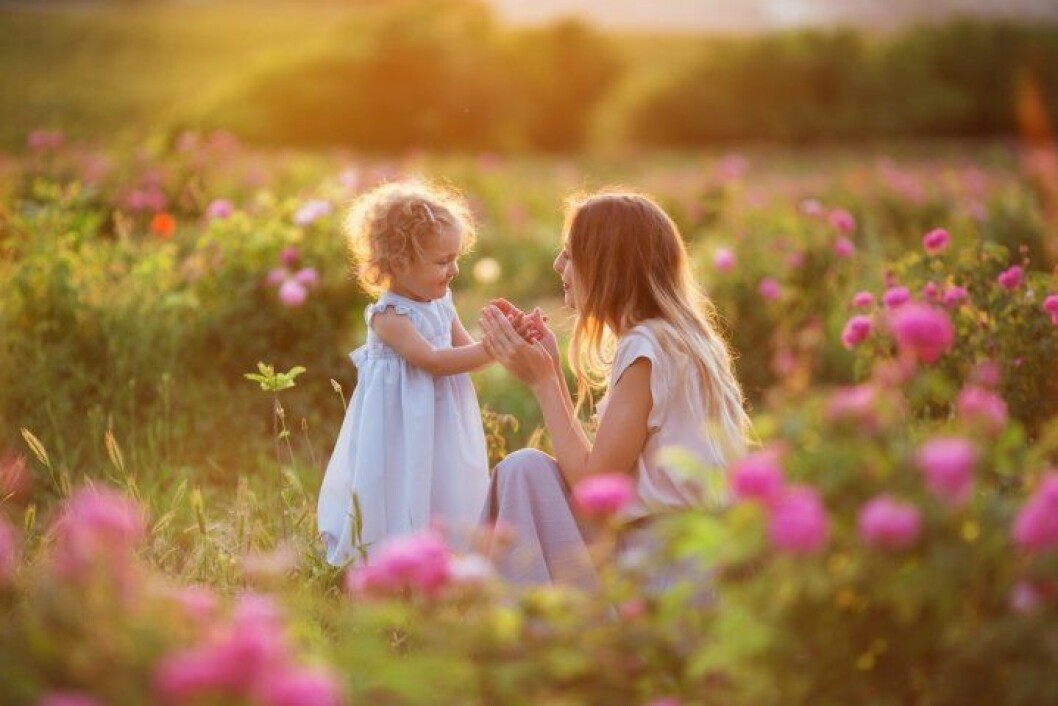 Barn och mamma luktar på blommor